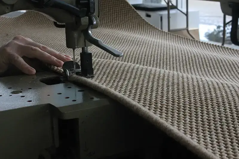 Machine serging action on a rug edge
