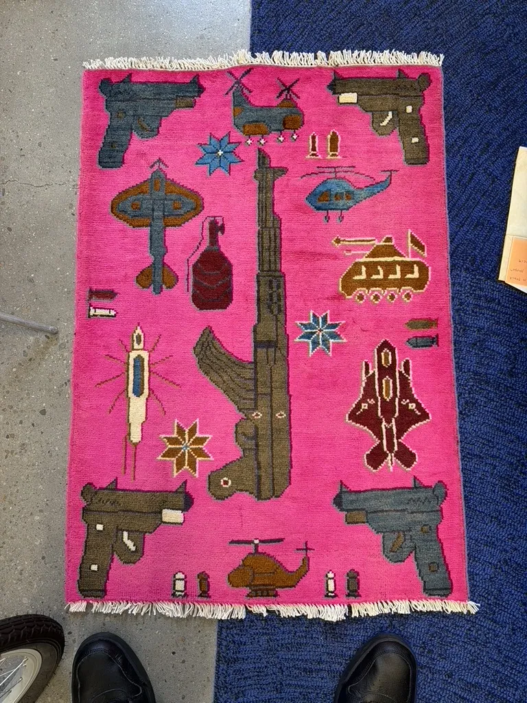 A new style Afghan war rug with weapon motifs on a pink field at the Fiber Specialties Boise shop