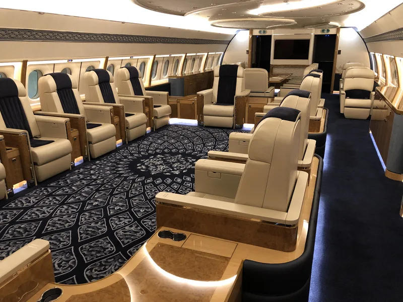 A detailed private jet cabin with patterned carpet and leather seating