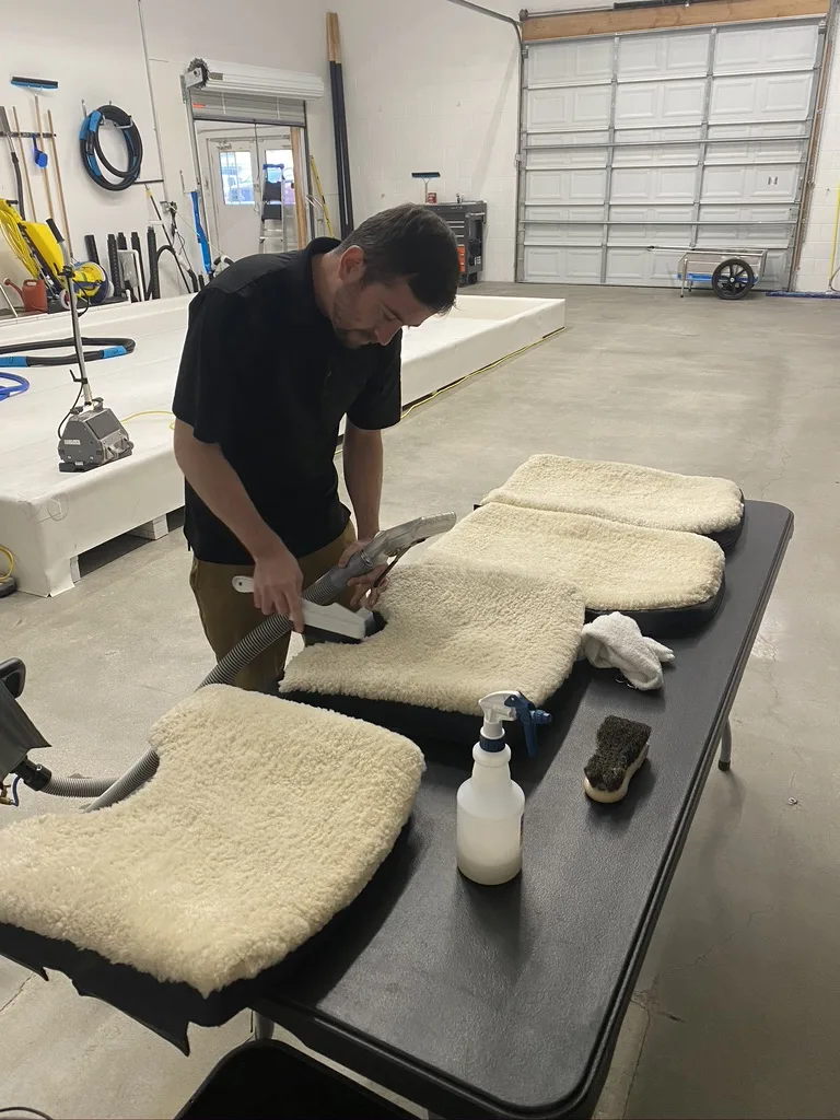 A technician cleaning wool sheepskin aircraft seat covers at the Fiber Specialties facility