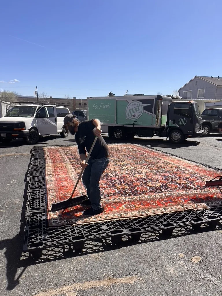 The circa 1890 Bijar rug being dusted outdoors at the start of its restoration in Boise