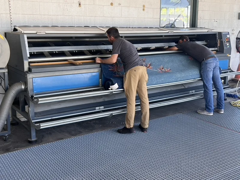 A blue Chinese rug on the dusting rack at the Fiber Specialties Boise facility before its wash