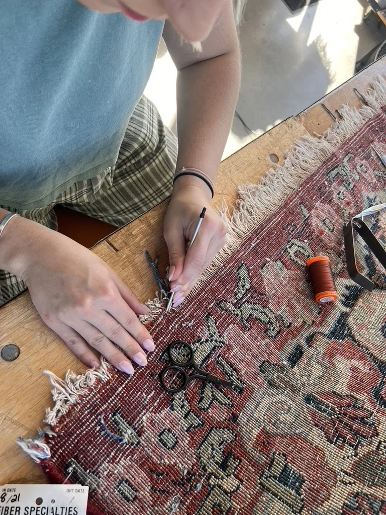 New fringe being knotted onto a hand-knotted rug by hand at the Fiber Specialties Boise workshop