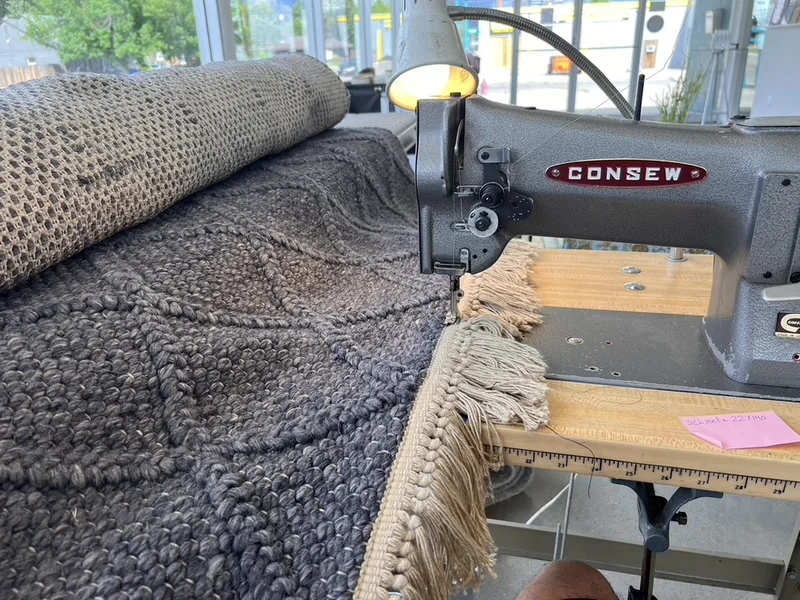 New fringe being machine stitched onto a gray rug at the Fiber Specialties Boise shop