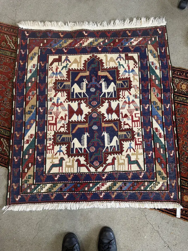 A hand-knotted wool rug with horse and bird motifs at the Fiber Specialties Boise shop