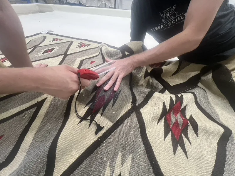 Two technicians hand washing a wool Navajo rug at the Fiber Specialties Boise facility