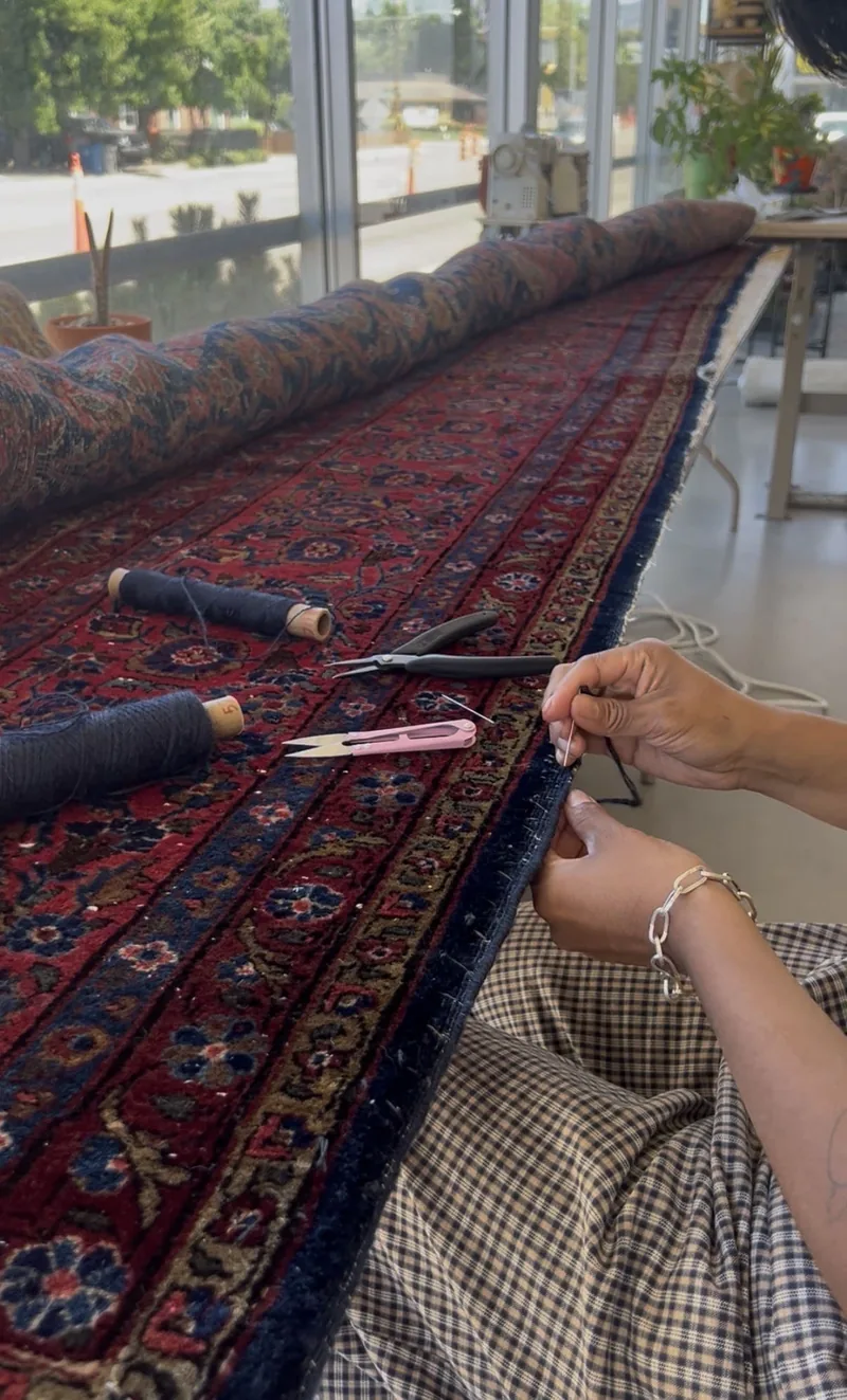 Hand fringe repair being stitched on a Persian rug at our Boise workshop