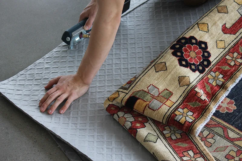 Custom-cut rug pads being prepared to fit a hand-knotted rug