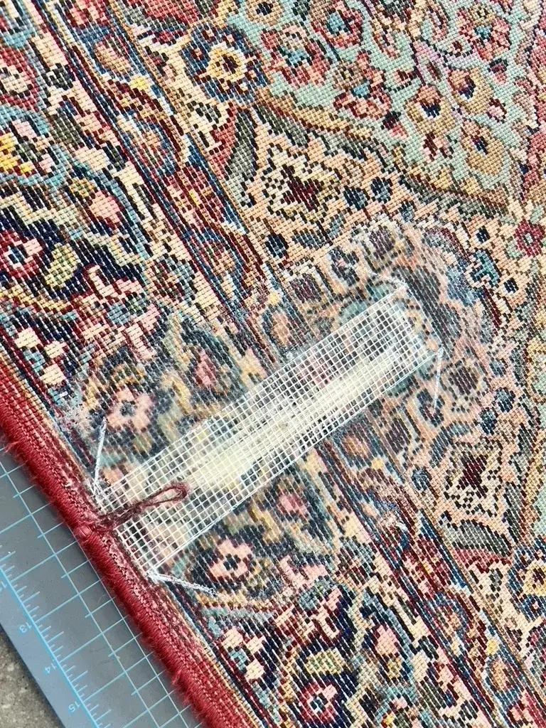 A hole in a Karastan style rug patched from the back at the Fiber Specialties Boise repair bench