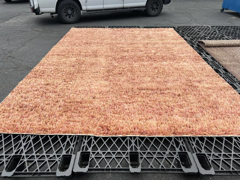A blush shag rug on the drying rack after washing and hand repair at the Fiber Specialties Boise facility