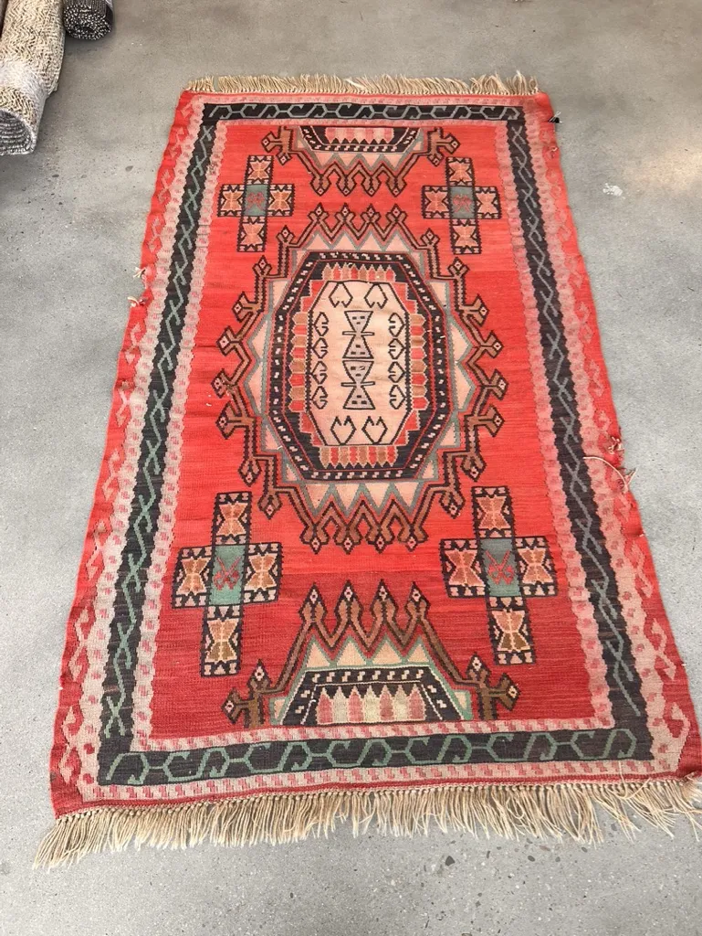 A red Turkish kilim after slitweave repair by hand at the Fiber Specialties Boise shop