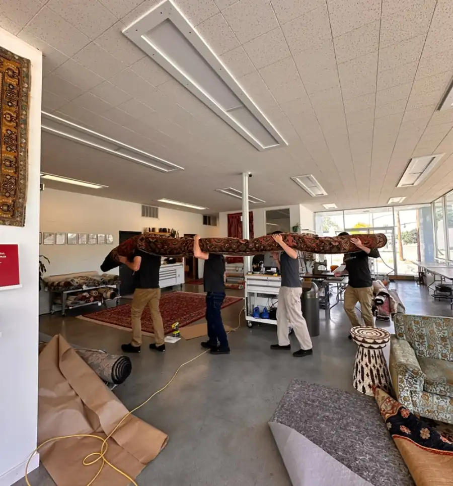 The Fiber Specialties team carrying a large hand-knotted rug