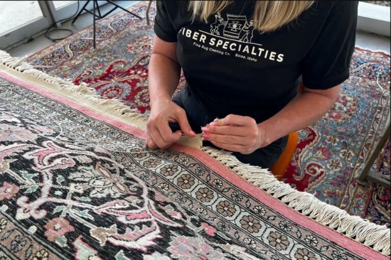 A woman hand sewing a rug fixing a small tear on the fringe.