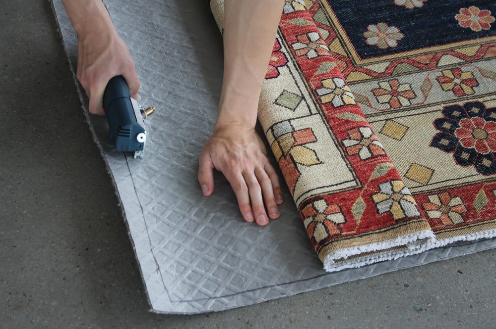 An individual utilizes a power tool to cut a rug, showcasing craftsmanship and attention to detail in the process.