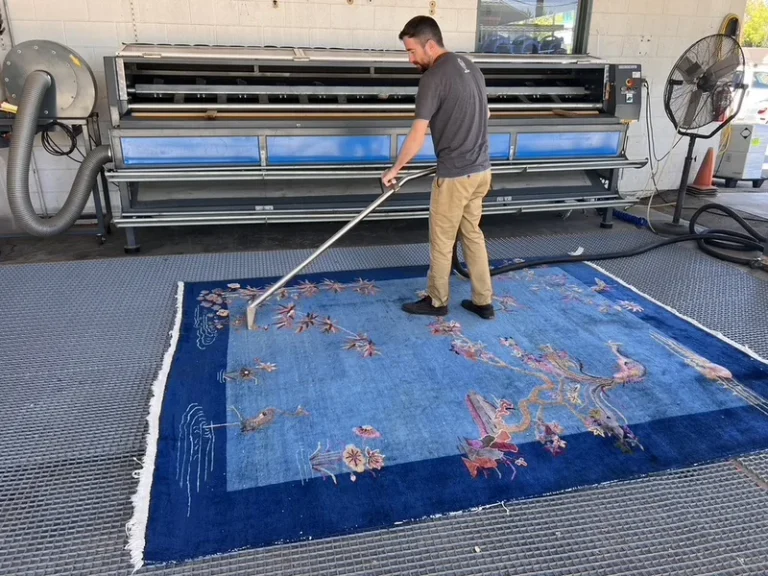 A blue Chinese rug being brushed through a full-immersion wash on the Fiber Specialties wash floor in Boise