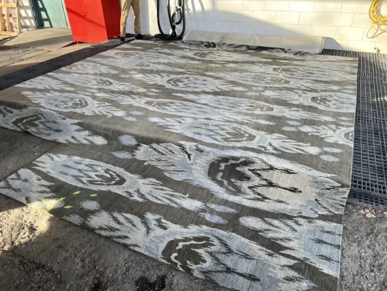 A moth damaged wool rug at the Fiber Specialties Boise facility with the eaten areas flagged in green tape