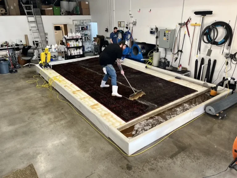 A technician scrubbing a submerged rug during a full-immersion wash at the Boise facility